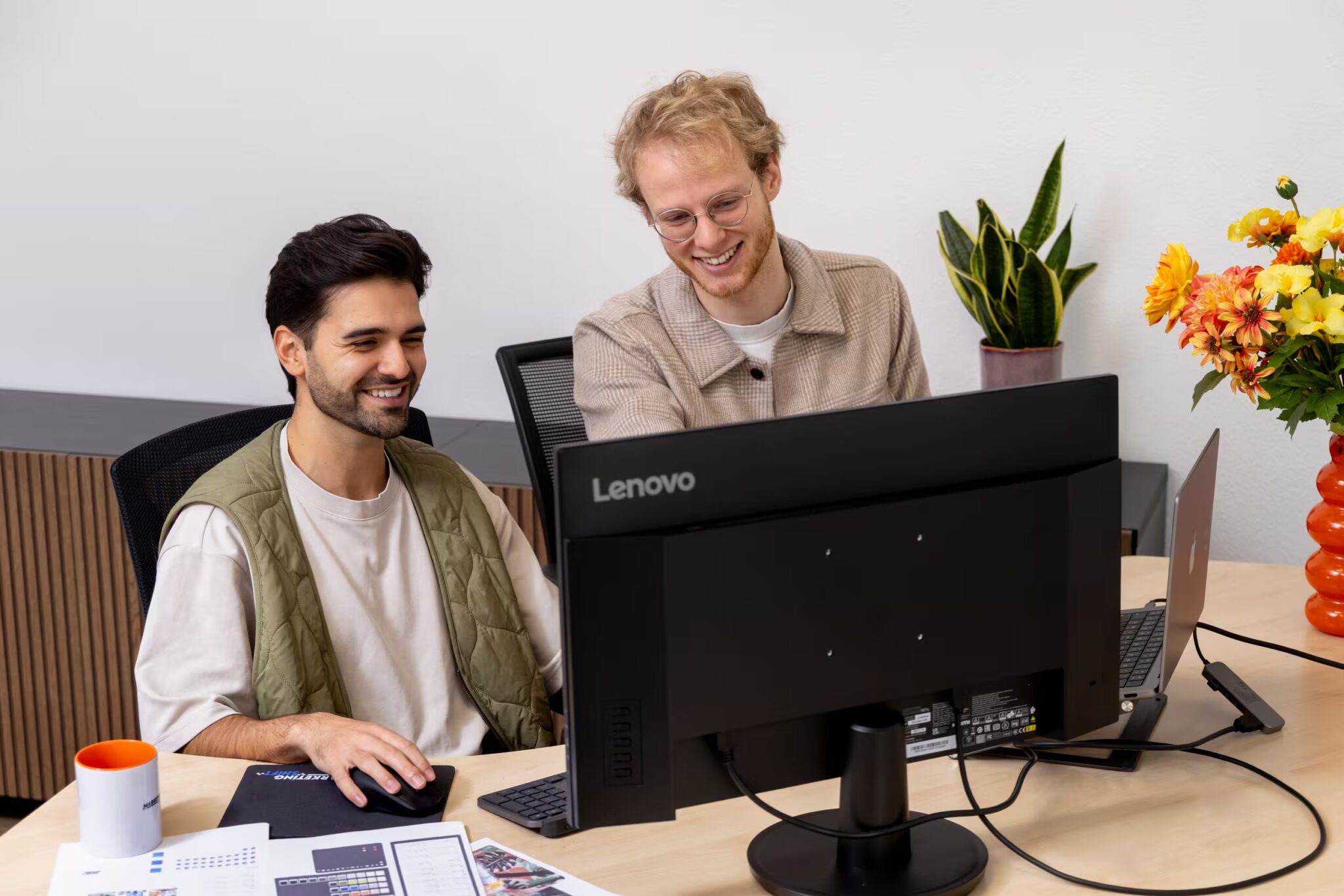 Twee collega's van Marketing Shift lachen achter een beeldscherm